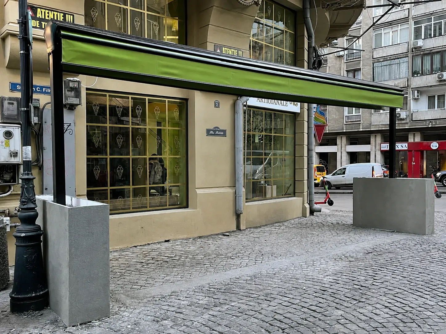 Stâlpii copertinei retractabile duble stabilizați cu blocuri de beton, fără ancorare în pavaj, pe Strada Ion C. Filitti