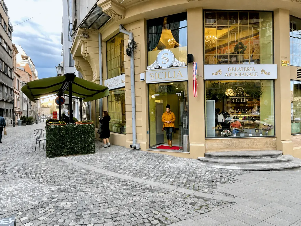 Vedere exterioară a unei copertine retractabile duble FER-AL instalate în fața unei gelaterii.