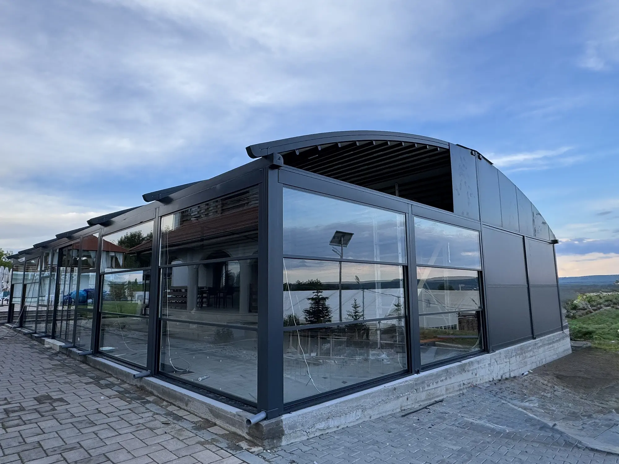 Structură curbată FER-AL cu închideri vitrate lângă piscină