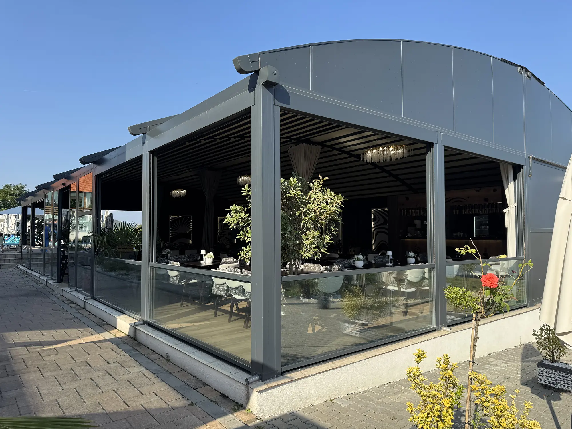 Vedere completă a pergolei curbate și a terasei restaurantului